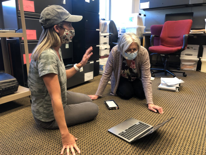 Delia and Frances talking on the ground at a laptop