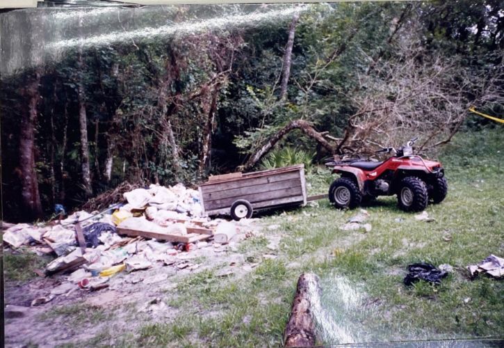 4-wheeler and attached trailer near a pile of trash