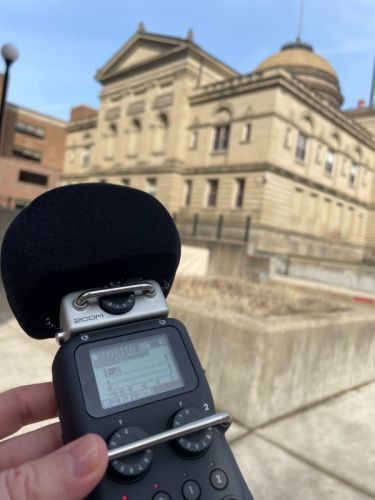audio recording device being held in front of a courthouse